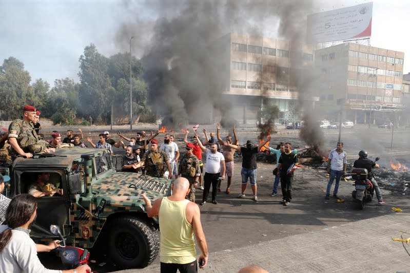 Demonstrators gesture as the Lebanese army soldiers drive near during a protest over deteriorating economic situation, in Dora