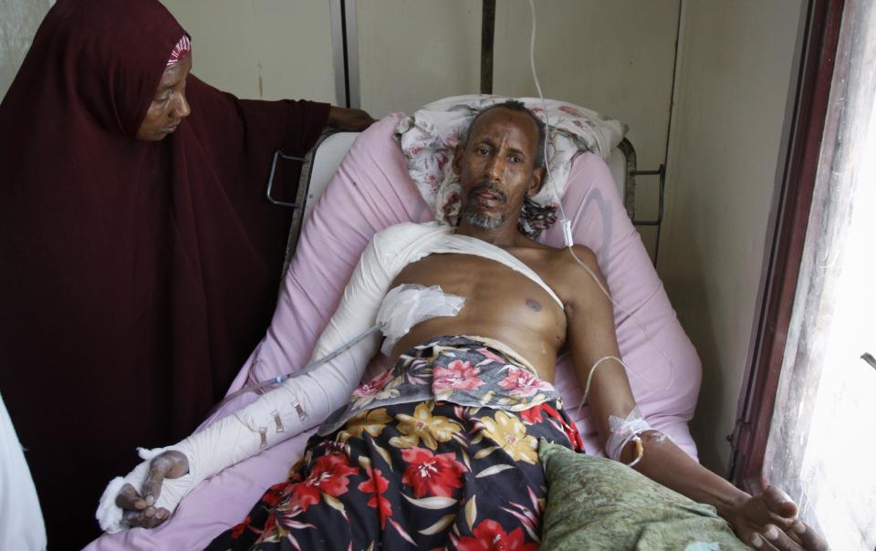 A Somali woman stands by the bedside of her husband who was wounded in a mortar attack, as he receives treatment at the Madina Hospital in the capital Mogadishu, Somalia, Wednesday, Feb. 5, 2014. Mortar fire from Islamic extremists has pummeled large parts of the Somali capital two nights this week, raising fears among residents of a return to the days of constant conflict and prompting government and security officials to spring into action. (AP Photo/Farah Abdi Warsameh)