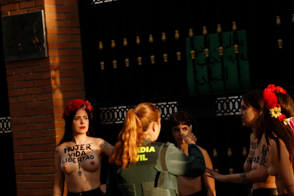 <p>SENSITIVE MATERIAL. THIS IMAGE MAY OFFEND OR DISTURB A civil guard officer asks Activists from the women's rights group FEMEN to remove their signs from the gate of the Embassy of Iran, as they protest following the death of Mahsa Amini, in Madrid, Spain, September 23, 2022. REUTERS/Susana Vera</p> 