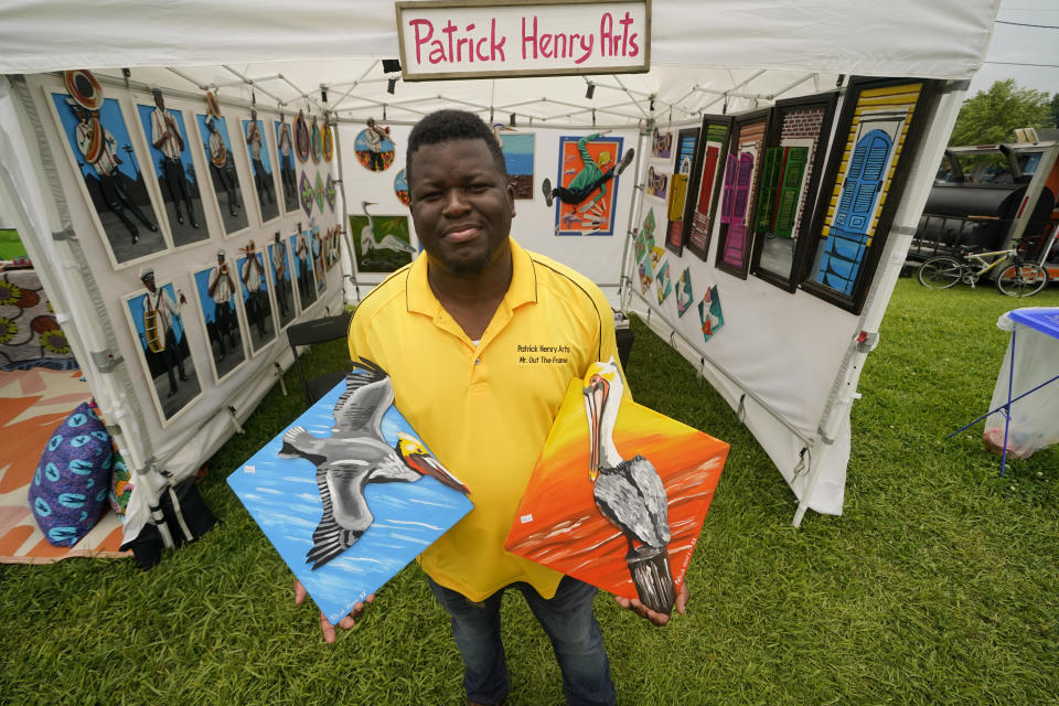 Local artist Patrick Henry shows some of his paintings of pelicans for sale at the Bayou Boogaloo festival in New Orleans, Saturday, May 21, 2022. The large coastal birds were among the first species declared endangered in the U.S. in 1970. Like bald eagles, their populations had been decimated by widespread DDT pesticide use, which thinned eggshells and prevented healthy chicks from hatching. (AP Photo/Gerald Herbert)