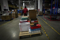 A worker pulls a trolley loaded with computer accessories at the Chinese online retailer JD.com's warehouse in Beijing on Tuesday, Nov. 9, 2021. China's biggest online shopping day, known as "Singles' Day" on Nov. 11, is taking on a muted tone this year as regulators crack down on the technology industry and President Xi Jinping pushes for "common prosperity." (AP Photo/Andy Wong)