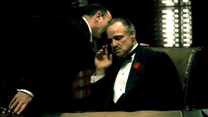 A man whispering something into Don Vito Corleone's ear in The Godfather.