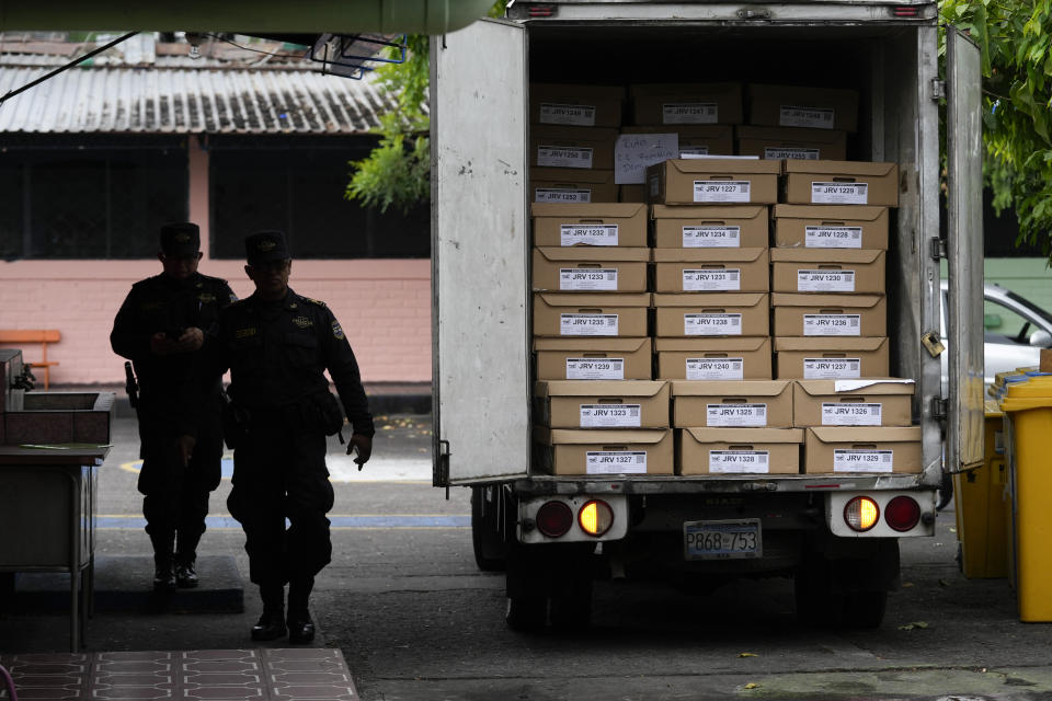 Policías de patrulla pasan junto a un vehículo que lleva boletas a un centro electoral el día antes de las elecciones generales en San Salvador, El Salvador, el sábado 3 de febrero de 2024. (AP Foto/Moisés Castillo)