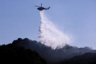 A A helicopter makes a water drop to put out hotspots in a wildfire in Topanga, west of Los Angeles, Monday, July 19, 2021. A brush fire scorched about 15 acres in Topanga today, initially threatening some structures before fire crews got the upper hand on the blaze, but one firefighter suffered an unspecified minor injury. (AP Photo/Ringo H.W. Chiu)