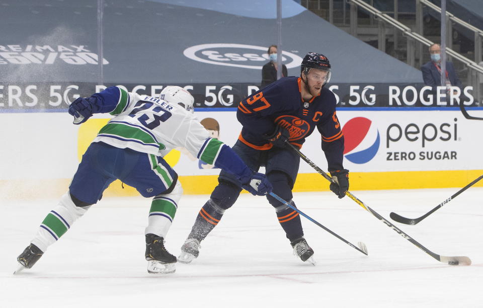 Edmonton Oilers' Connor McDavid (97) makes a move to get past Vancouver Canucks' Alexander Edler (23) during second-period NHL hockey action in Edmonton, Alberta, Thursday, Jan. 14, 2021. (Jason Franson/The Canadian Press via AP)