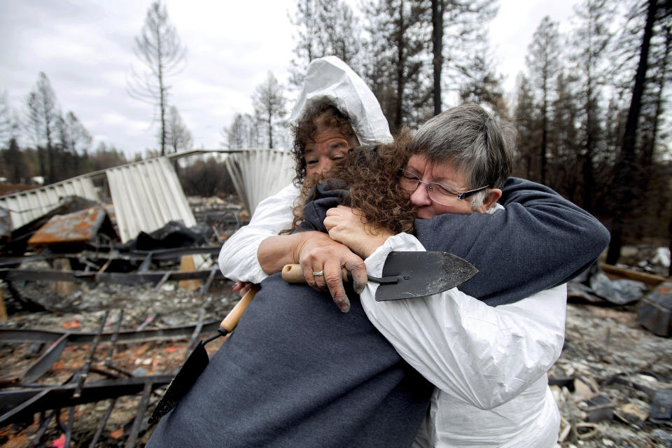 In this Feb. 8, 2019, photo, Carol Beall, right, hugs friends as they comb through the remains of her residence, destroyed by the Camp Fire, in Paradise, Calif. It was the first time that Beall, who lived in the the Ridgewood Mobile Home Park, returned to Paradise since fleeing the blaze in November 2018. In the 100 days since a wildfire nearly burned the town of Paradise off the map, the long recovery is just starting. Work crews have been cutting down trees and clearing burned-out lots, but Paradise is mostly a ghost town where survivors still dig for keepsakes in the foundations of their homes. (AP Photo/Noah Berger)