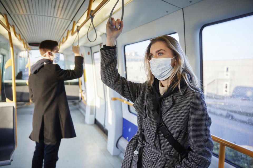 Young woman inside train, wearing a virus protective face mask