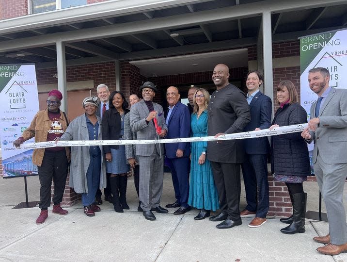 Developer Chinedum Ndukwe, fourth from the right, prepares for the ribbon-cutting ceremony for one of his latest affordable housing developments, the Blair Lofts Apartments in Cincinnati's Avondale neighborhood.