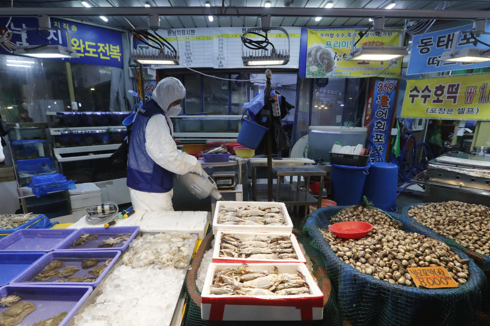 A worker wearing protective gears sprays disinfectant as a precaution against the coronavirus at a market in Seoul, South Korea, Monday, Feb. 24, 2020. South Korean President Moon Jae-in said his government had increased its anti-virus alert level by one notch to “Red,” the highest level. It allows for the temporary closure of schools and reduced operation of public transportation and flights to and from South Korea. (AP Photo/Ahn Young-joon)