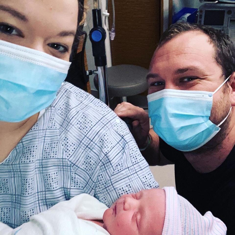 Ms Thompson and her husband are pictured wearing masks while she holds their newborn. Source: Supplied