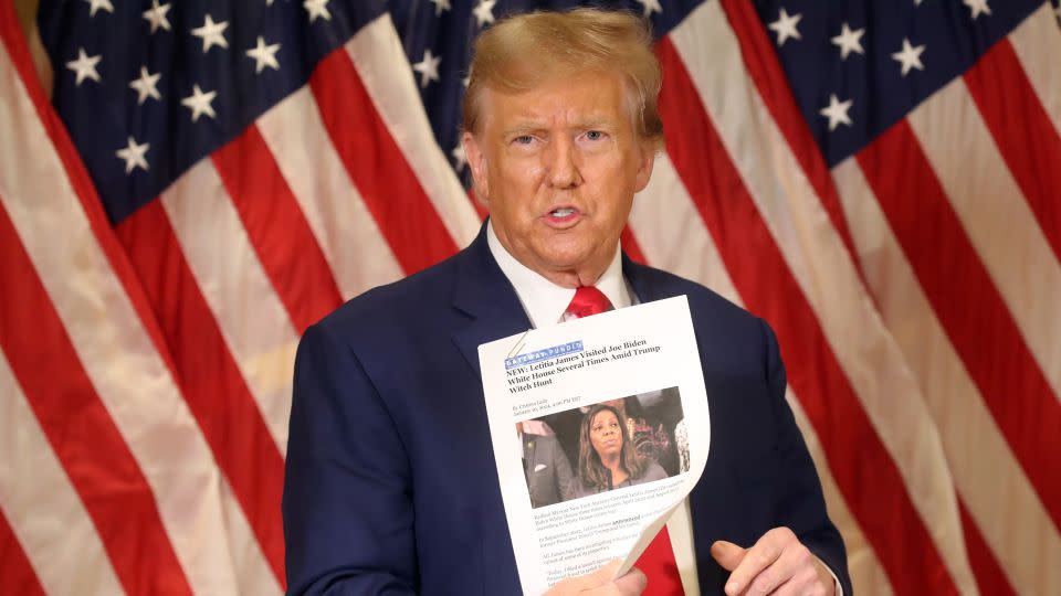 Donald Trump holds up a news story about New York Attorney General Letitia James as he speaks to the media at one of his properties at 40 Wall Street following closing arguments at his civil fraud trial on January 11, 2024 in New York City. - Spencer Platt/Getty Images