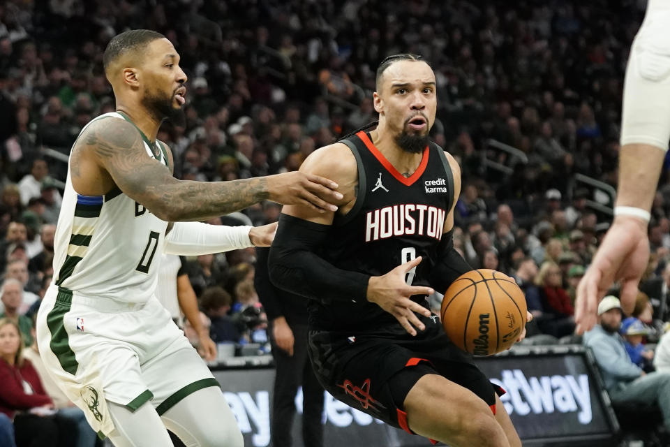 Houston Rockets' Dillon Brooks, right, drives to the basket against Milwaukee Bucks' Damian Lillard (0) during the first half of an NBA basketball game Sunday, Dec. 17, 2023, in Milwaukee. (AP Photo/Aaron Gash)