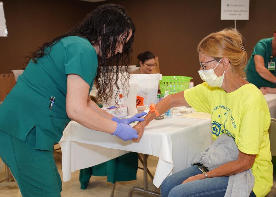 Suesen Dresch, left, from ProMedica Charles and Virginia Hickman Hospital, prepares to draw blood from Laura VanSickle of Adrian for a general health screening June 9, 2022, during Health Check clinic in Adrian, hosted by ProMedica and the United Way of Monroe/Lenawee Counties.