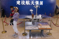 Visitors to an exhibition on China's space program pose for photos next to a life size model of the Chinese Mars rover Zhurong, named after the Chinese god of fire, at the National Museum in Beijing on Thursday, May 6, 2021. China has landed a spacecraft on Mars for the first time in the latest advance for its space program. The official Xinhua News Agency said Saturday, May 15, that the lander had touched down, citing the China National Space Administration. Chinese characters read: Build a Space Power. (AP Photo/Ng Han Guan)