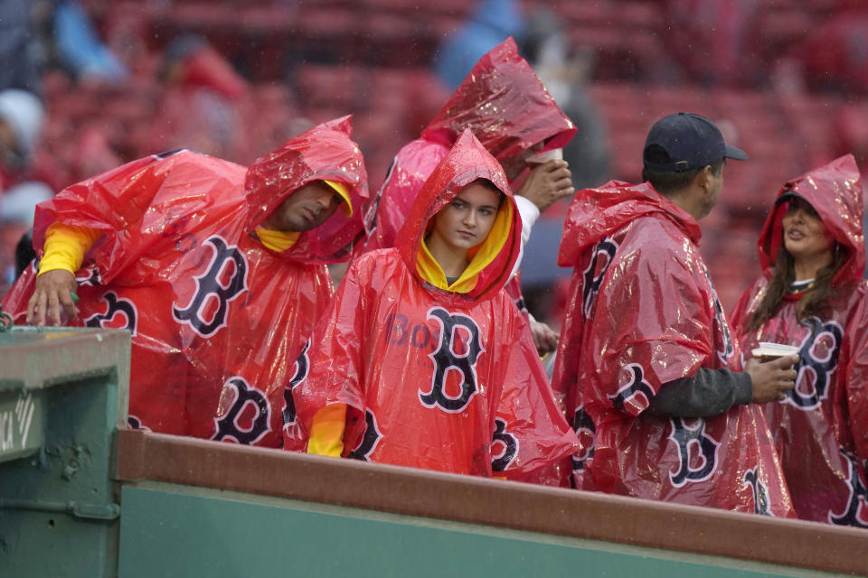 Fans wear ponchos as they look into the Boston Red Sox dugout during a rain delay of a baseball game against the Chicago White Sox, Sunday, Sept. 24, 2023, in Boston. (AP Photo/Steven Senne)