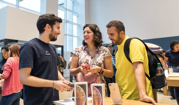 An Apple employee shows consumers the new iPhone models.