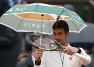 Tennis - French Open - Roland Garros - Novak Djokovic of Serbia v Roberto Bautista Agut of Spain - Paris, France - 31/05/16. Djokovic holds an umbrella as he arrives on the court. REUTERS/Gonzalo Fuentes