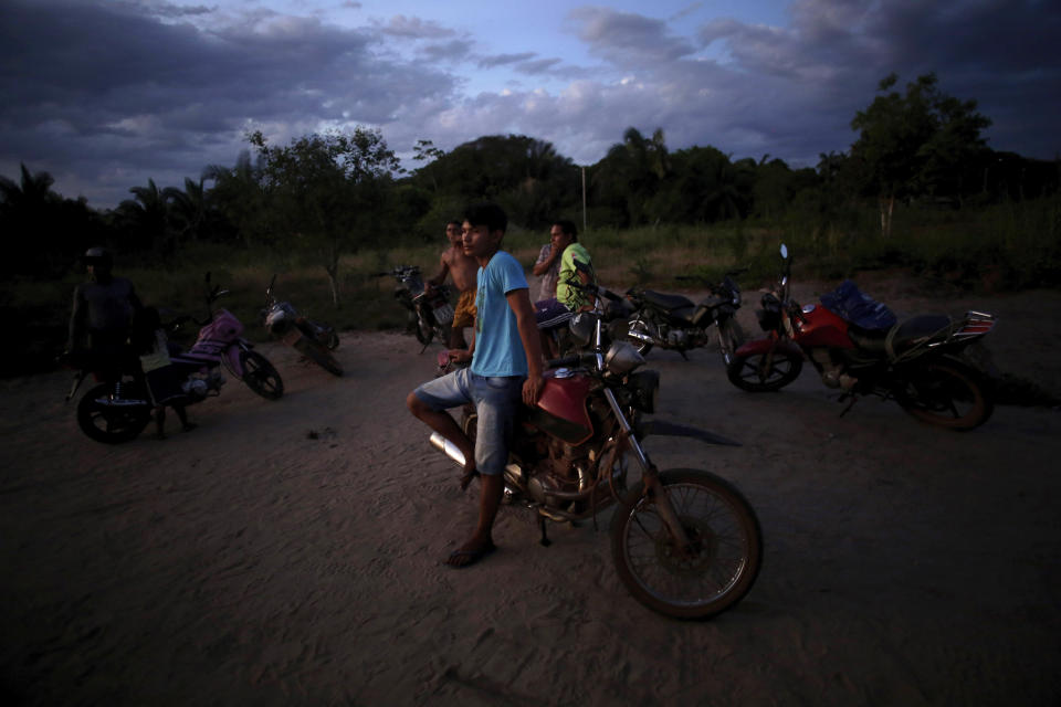 Tenetehara Indigenous men gather with their motorcycles at dusk in the Alto Rio Guama Indigenous Territory, where they have enforced six months of isolation during the COVID-19 pandemic, near the city of Paragominas, state of Para, northern region of Brazil, Monday, Sept. 7, 2020. The Indigenous group, also known as Tembe, held a festival this week to celebrate and give thanks that none of their members have fallen ill with COVID-19, after closing their area off in March. (AP Photo/Eraldo Peres)