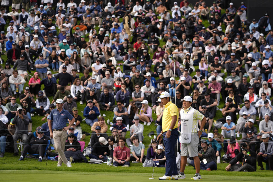 Hideki Matsuyama, of Japan, and caddie wait on the 18th green during the final round of the Genesis Invitational golf tournament at Riviera Country Club, Sunday, Feb. 18, 2024, in the Pacific Palisades area of, Los Angeles. (AP Photo/Ryan Sun)