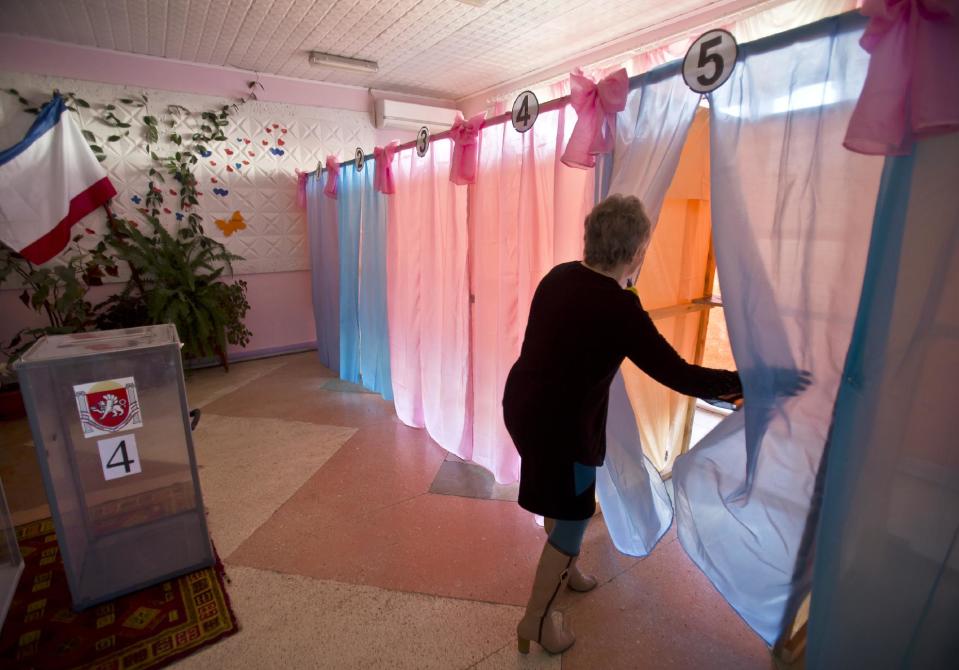 Svetlana Kalisetskaya, chairman of polling committee, checks a voting cabin after completing preparations for Sunday's referendum at a polling station in Perevalne, Ukraine, Saturday, March 15, 2014. Tensions are high in the Black Sea peninsula of Crimea, where a referendum is to be held Sunday on whether to split off from Ukraine and seek annexation by Russia.(AP Photo/Vadim Ghirda)