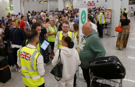 Passengers are seen at Thomas Cook check-in points at Mallorca Airport after the world's oldest travel firm collapsed, in Palma de Mallorca