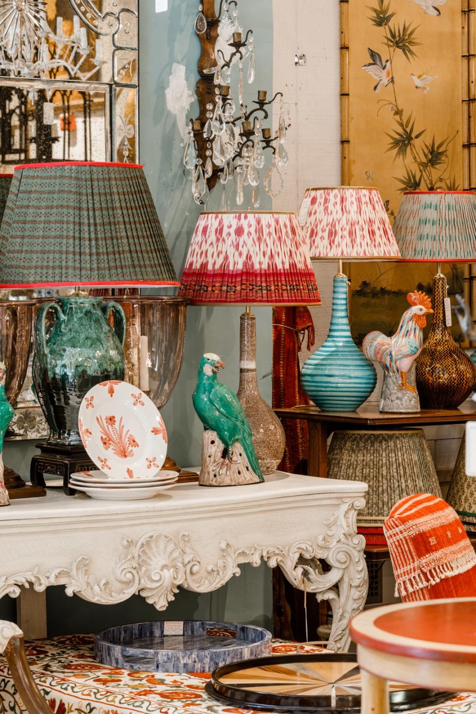 Two bird figurines roost on an elaborate table with several glazed lamps