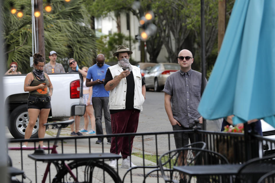 Service and entertainment industry employees who have been laid off due to the new coronavirus pandemic, exercise social distancing as they line up for meals cooked by chef Isaac Toups at his restaurant Toups Meatery in New Orleans, Friday, March 27, 2020. While rich in history and culture, New Orleans is economically poor, and the people here are not necessarily well-positioned to weather this latest storm. (AP Photo/Gerald Herbert)