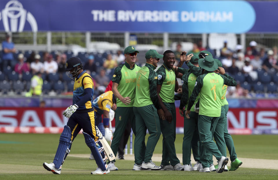 Sri Lanka's captain Dimuth Karunaratne, left, walks off after being dismissed by South Africa's bowler Kagiso Rabada, middle, during the Cricket World Cup match between Sri Lanka and South Africa at the Riverside Ground in Chester-le-Street, England, Friday, June 28, 2019. (AP Photo/Scott Heppell)