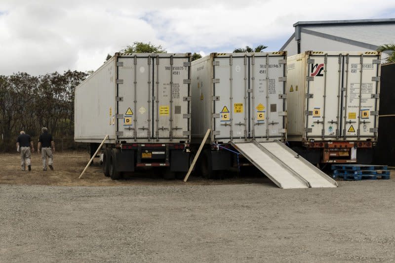 Workers walk by three large containers parked next to the Forensic Facility in Wailuku, Hawaii, on Monday. The three containers are refrigerated and can be used for body storage. Photo by Etinne Laurent/EPA-EFE