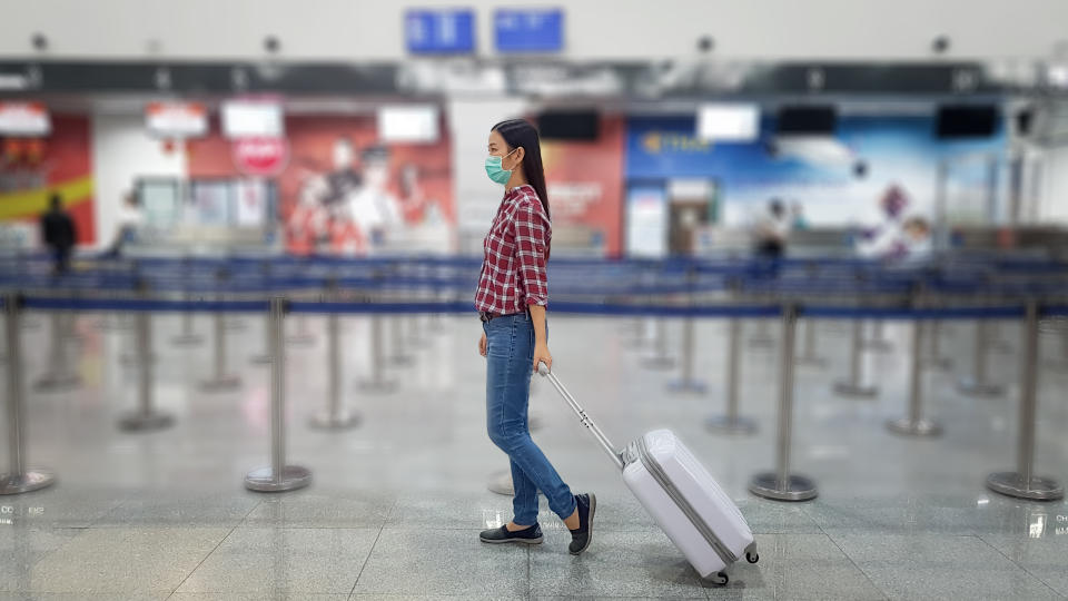 Asian tourist with luggage ,wearing mask to prevent coronavirus during travel time at the airport 