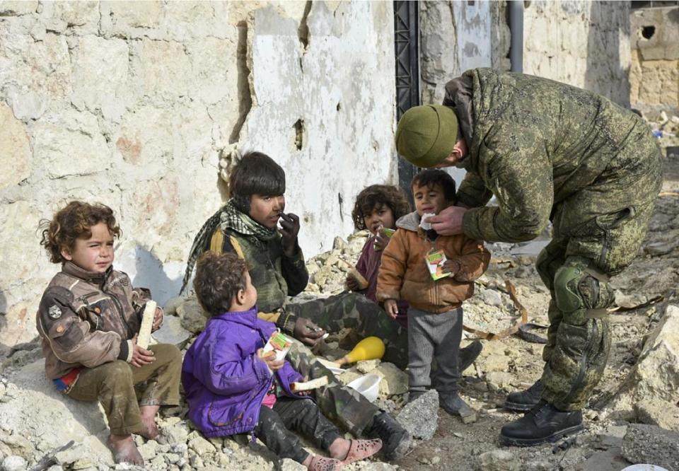 This undated handout photo released by the Russian Defense Ministry claims to show a Russian Military engineer distributing juice to local children in Aleppo, Syria.(Russian Defense Ministry Press Service photo via AP)