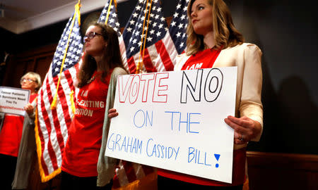 Women hold signs during a press conference held by U.S. Sen. Bob Casey, D-Pa., to speak out against the latest Republican effort to repeal Obamacare on Capitol Hill in Washington, U.S., September 25, 2017. REUTERS/Kevin Lamarque
