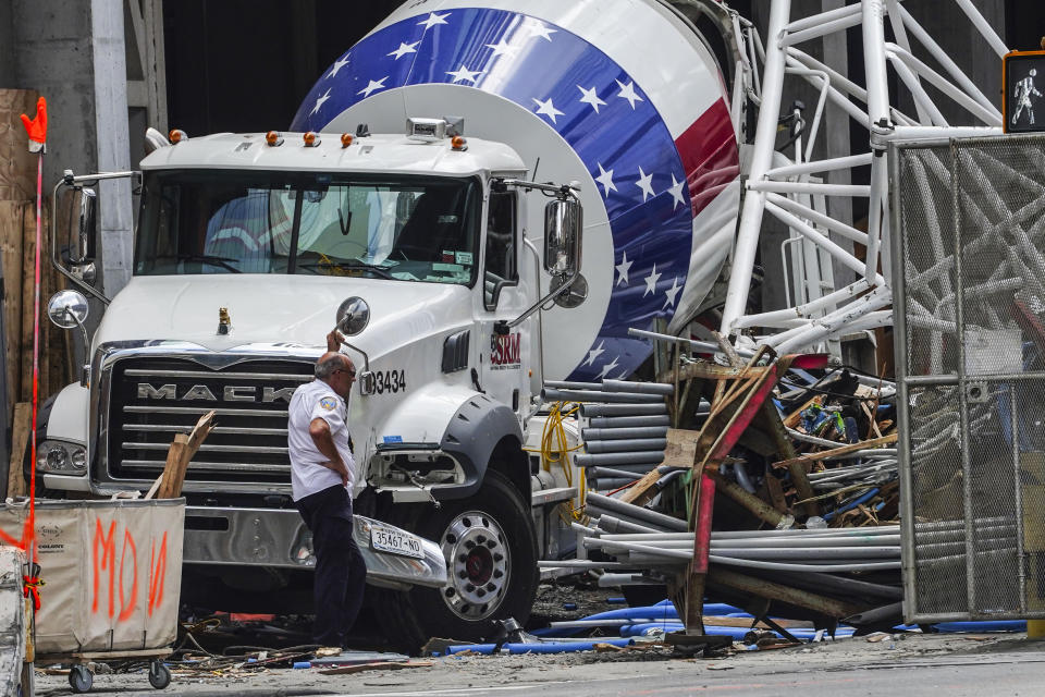 Part of the extension arm from a hi-rise construction crane lies crashed against a cement truck, Thursday July 27, 2023, in New York. The crane caught fire yesterday, losing the long arm which smashed into a nearby building as it plummeted to the street. (AP Photo/Bebeto Matthews)