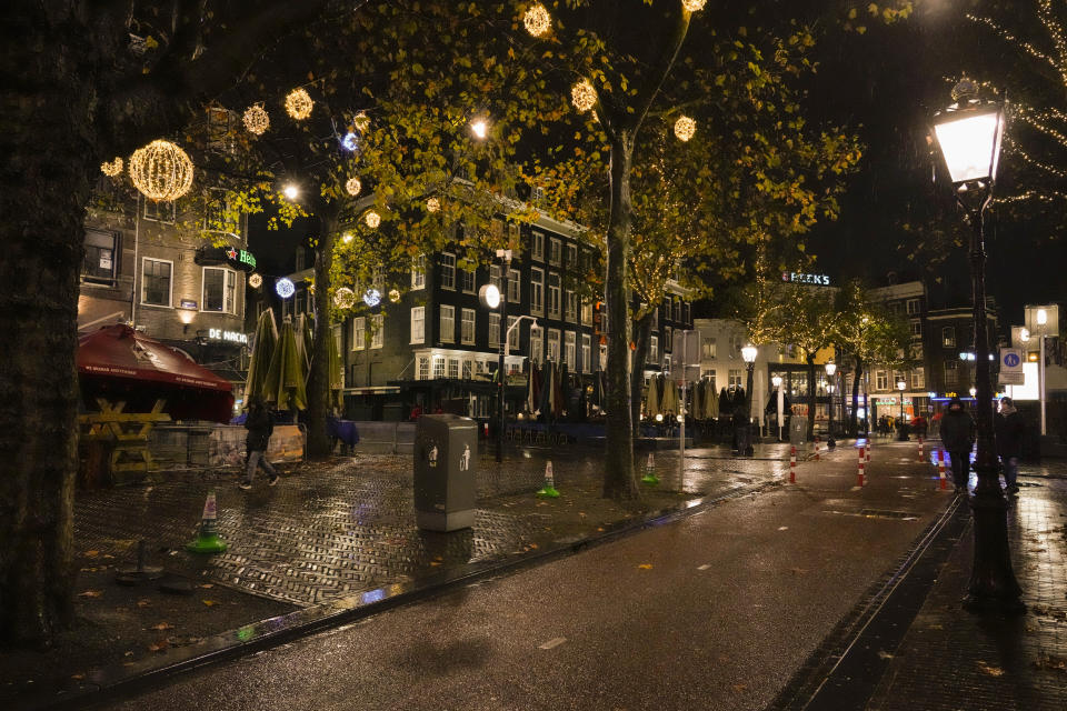 Closed bars and restaurants under a partial lockdown are seen on a near-deserted Rembrandt plein, or Rembrandt Square, in Amsterdam, Netherlands, Friday, Nov. 26, 2021. The Dutch government tightened its lockdown Friday night amid swiftly rising infections and ICU admissions. (AP Photo/Peter Dejong)