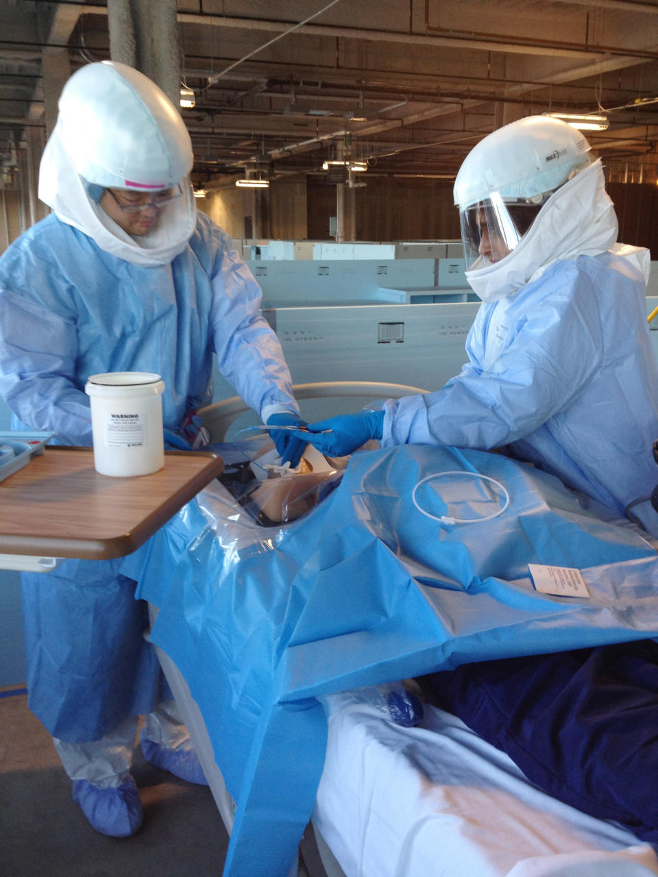 In this Monday, Oct. 6, 2014, photo Dr. Mark Abe, left, and Dr. Neethi Pinto learn how to perform a medical procedure on a patient mannequin while wearing protective gear during Ebola preparedness training at the University of Chicago. U.S. hospitals are preparing for possible Ebola patients; the only one diagnosed so far in this country is being treated in Texas, while the outbreak in Africa has killed more than 3,400 people. (AP Photo/Lindsey Tanner)