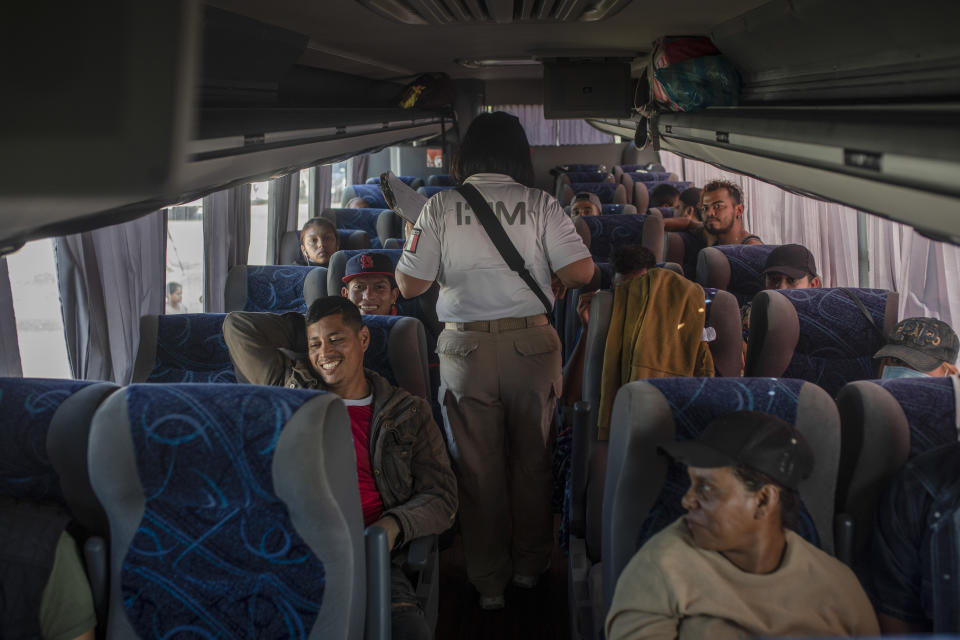 Nicaraguan migrant Benjamin Villalta, left, smiles as he and other migrants, mostly Central American, listen to the instructions of an immigration officer after abandoning their journey north, in Ciudad Isla, southern Veracruz state, Mexico, Nov. 25, 2021. The 39-year-old Nicaraguan couldn’t believe that a Mexican immigration office would open in the middle of the night to give him and some 40 other migrants one-year humanitarian visas allowing them to move about Mexico and work. (AP Photo/Felix Marquez)