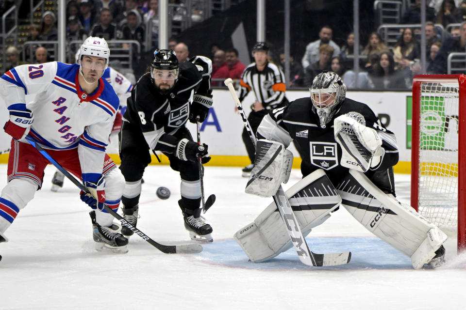 New York Rangers left wing Chris Kreider, left, deflects the puck as he is defended by Los Angeles Kings defenseman Drew Doughty (8) and goaltender David Rittich during the third period of an NHL hockey game Saturday, Jan. 20, 2024, in Los Angeles. (AP Photo/Jayne-Kamin-Oncea)