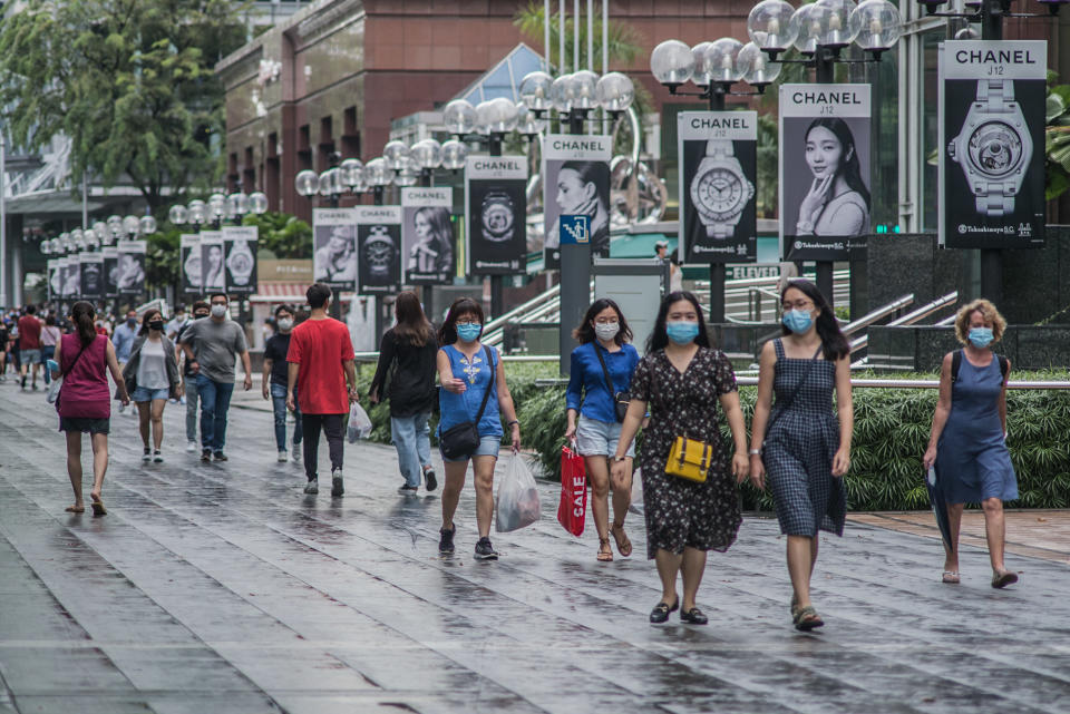 SINGAPORE - 2020/07/25: People wearing protective masks walk along Orchard Road, a famous shopping district in Singapore.  As of 26 July 2020, the total number of confirmed COVID-19 cases in Singapore are at 50,369. (Photo by Maverick Asio/SOPA Images/LightRocket via Getty Images)