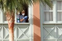 Los huéspedes con máscaras protectoras miran desde una ventana del H10 Costa Adeje Palace, que está cerrado después de que se hayan detectado casos de coronavirus allí en Adeje, en la isla española de Tenerife, España