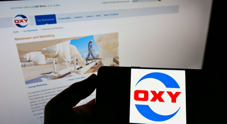 Person holding cellphone with logo of American company Occidental Petroleum Corp. (OXY) on screen in front of website. Focus on phone display. Unmodified photo.