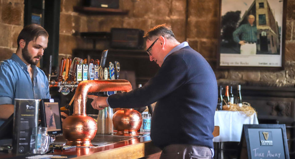 A barman pours a customer a bottle of beer to take away at the Hero of Waterloo pub in The Rocks. Source: Getty