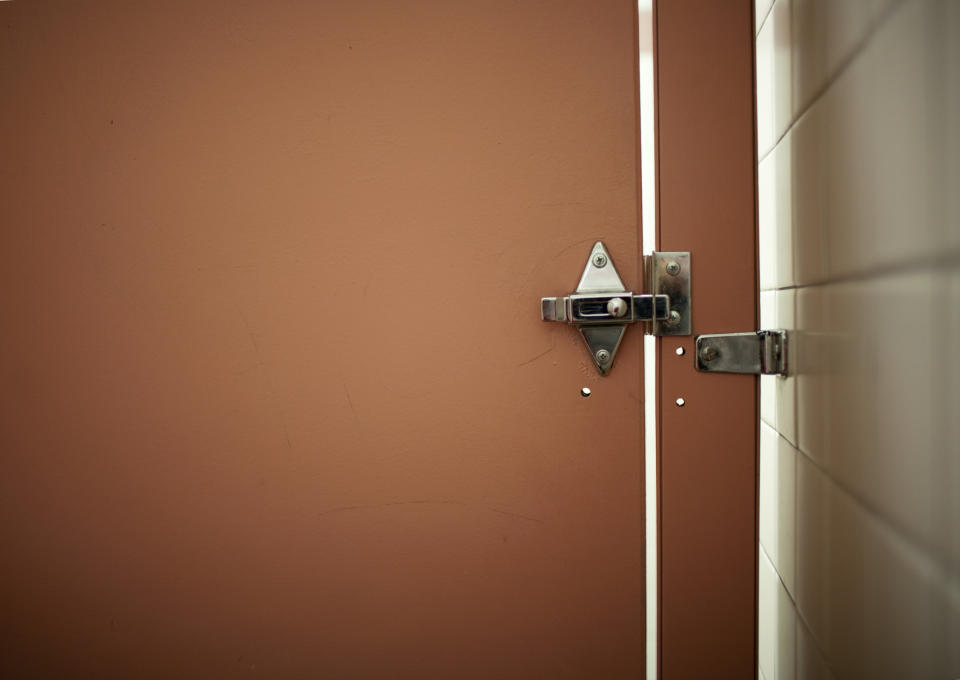 Door latch on a partially open door, against an orange background