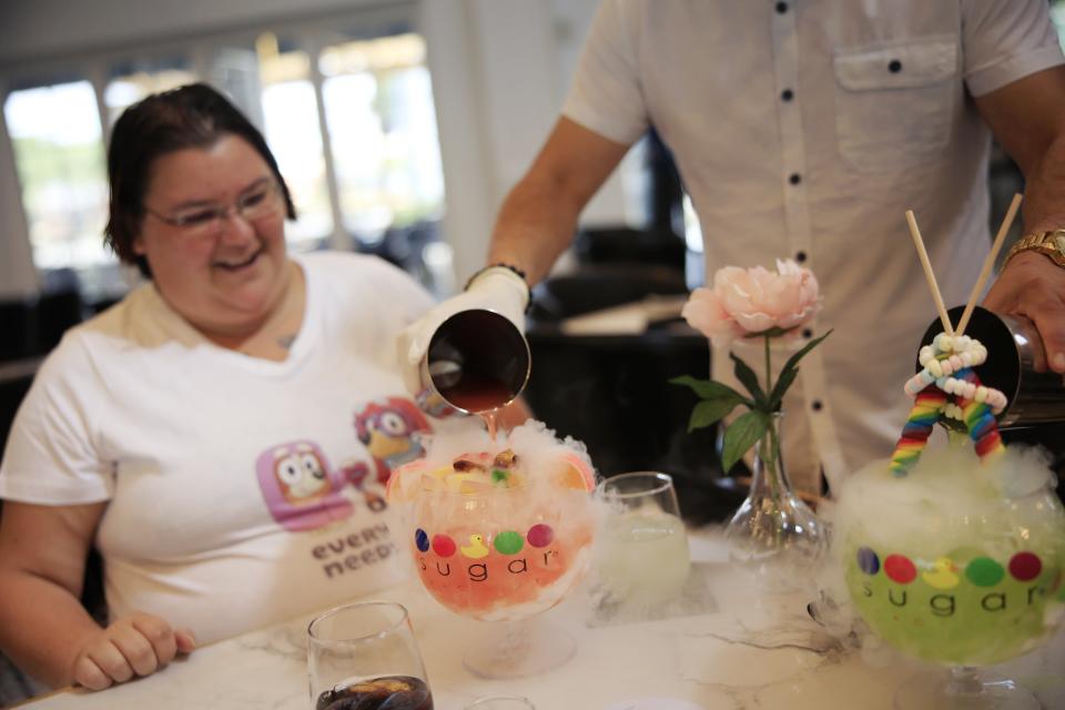 Jesika Riddle smiles as lollipop passion and candy shop drinks are poured for her birthday lunch by Corporate Director Carlos Ramirez Wednesday, March 29, 2023, at Sugar Factory American Brasserie at 4910 Big Island Drive at The Markets at St. Johns in Jacksonville. The new dining spot opened Tuesday and offers savory meals, craft cocktails, couture candy and more. [Corey Perrine/Florida Times-Union]

Jki 032923 Sugar Factory 01