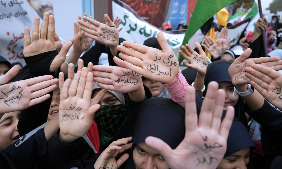 Iranian school girls show their hands with pro-government slogans and an anti-Israeli slogan which reads in Farsi: "Death to Israel", during a rally in front of the former U.S. Embassy in Tehran, Iran, marking 44th anniversary of the seizure of the embassy by militant Iranian students, Saturday, Nov. 4, 2023. (AP Photo/Vahid Salemi)