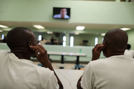 Men share a pair of headphones to watch television in a dormitory at the Adelanto immigration detention center, which is run by the Geo Group Inc (GEO.N), in Adelanto, California, U.S., April 13, 2017. REUTERS/Lucy Nicholson