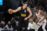 Denver Nuggets center Nikola Jokic, left, is defended by Phoenix Suns forward Kevin Durant during the first half of an NBA basketball game Wednesday, March 27, 2024, in Denver. (AP Photo/David Zalubowski)