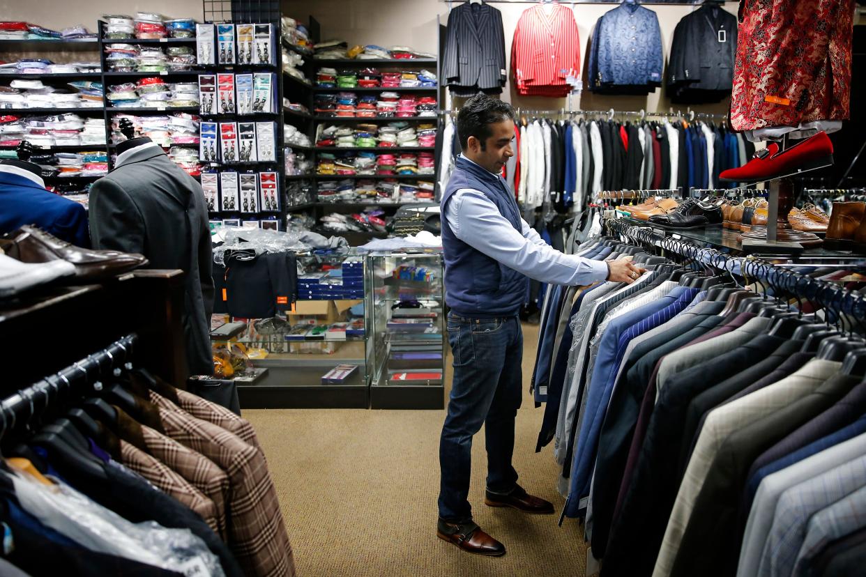 Andy Mahbubani, owner of GQ Fashions Fine Menswear, looks over inventory inside the store before reopening in May 2020 after being forced to close during the early days of the COVID-19 pandemic.