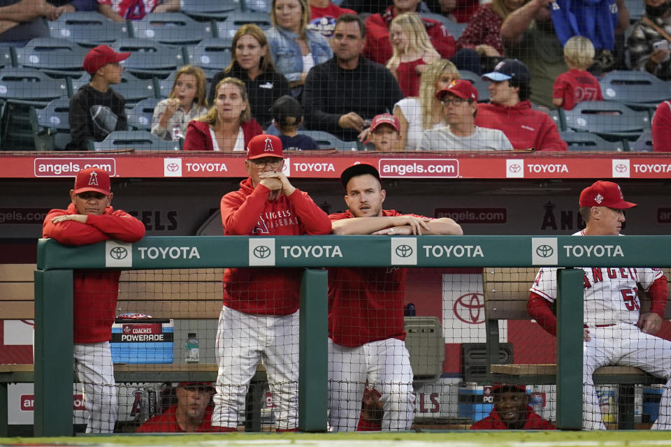 Los Angeles Angels manager Joe Maddon, center left, and center fielder Mike Trout, center right, stand in the dugout during the first inning of a baseball game against the Oakland Athletics Friday, Sept. 17, 2021, in Anaheim, Calif. (AP Photo/Ashley Landis)