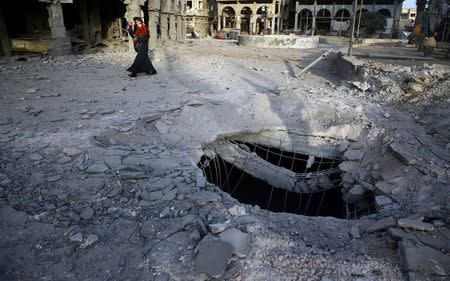 A Syrian woman walks past damaged buildings in Douma, in the eastern Damascus suburb of Ghouta, Syria November 15, 2017. REUTERS/Bassam Khabieh