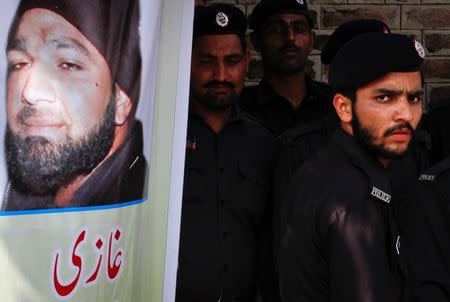 A police officer stands guard next to an image of convicted killer Mumtaz Qadri, outside Adiala Jail where Qadri is being held, in Rawalpindi, October 1, 2011. REUTERS/Faisal Mahmood